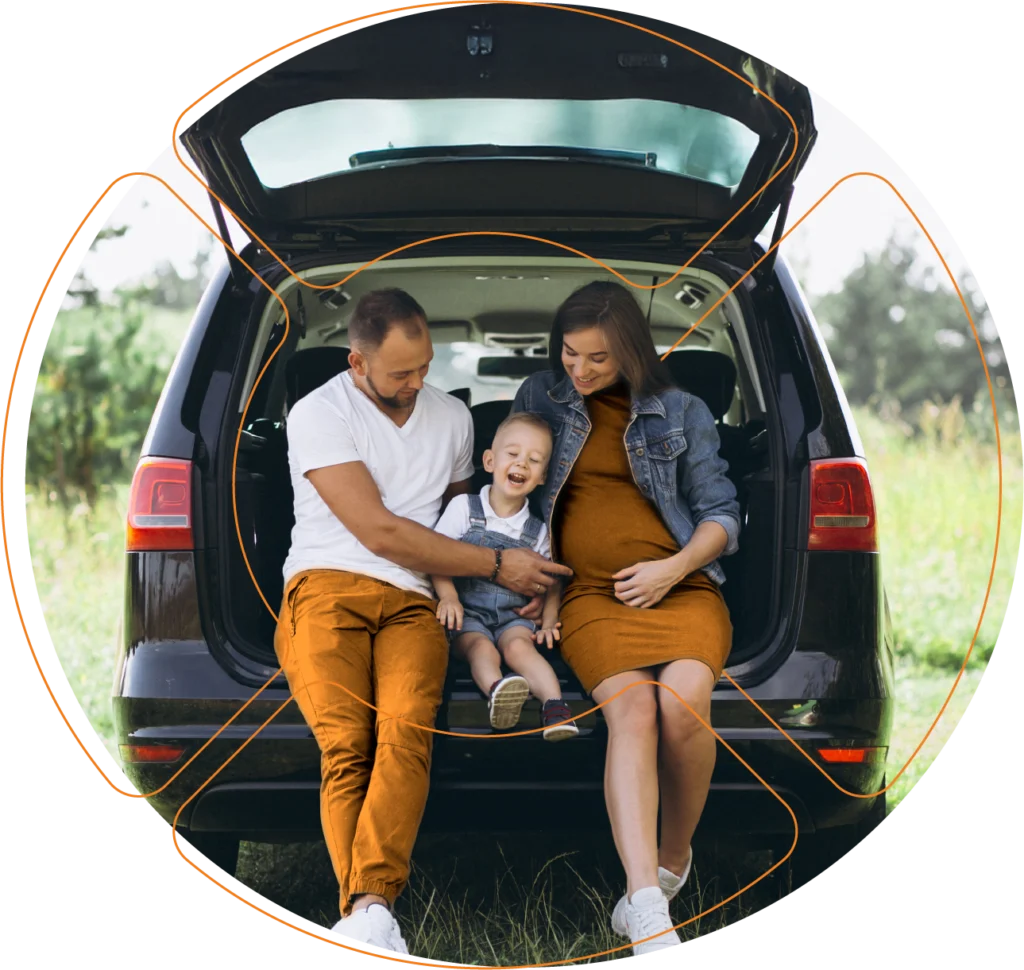 Uma família (pai mãe e filho) felizes em um veículo que conta com o seguro de carro da Cota Fácil.